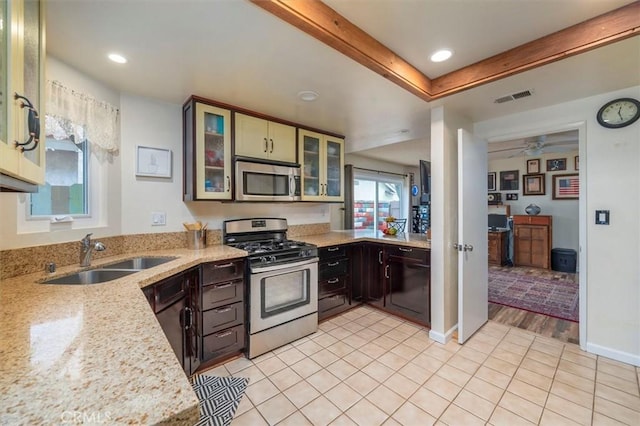 kitchen with a ceiling fan, light stone counters, a sink, stainless steel appliances, and visible vents