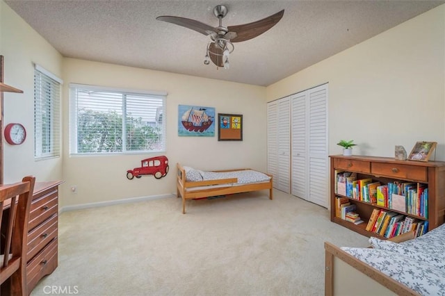 bedroom featuring a closet, a textured ceiling, baseboards, and light carpet
