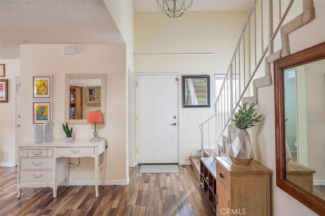 foyer featuring stairway, baseboards, wood finished floors, and a textured ceiling