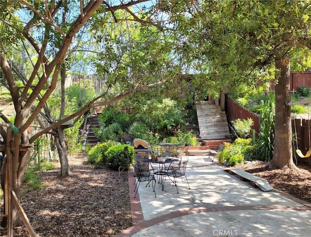 exterior space featuring outdoor dining area, fence, a patio area, and stairs