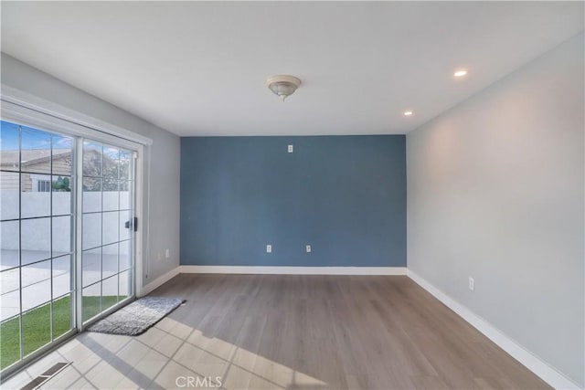 spare room with baseboards, recessed lighting, and wood finished floors