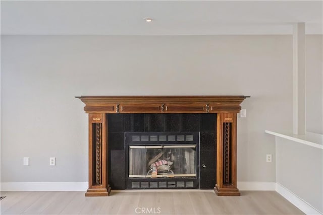 details with baseboards, wood finished floors, and a tile fireplace
