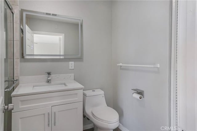 bathroom with toilet, an enclosed shower, and vanity