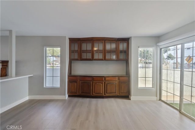 unfurnished dining area with light wood-style flooring and baseboards