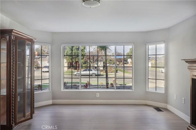 unfurnished dining area with visible vents, baseboards, and wood finished floors