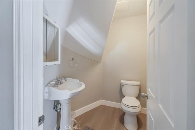 half bath featuring toilet, wood finished floors, and baseboards