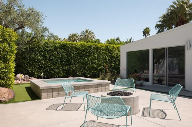 view of patio / terrace featuring an in ground hot tub and a fire pit