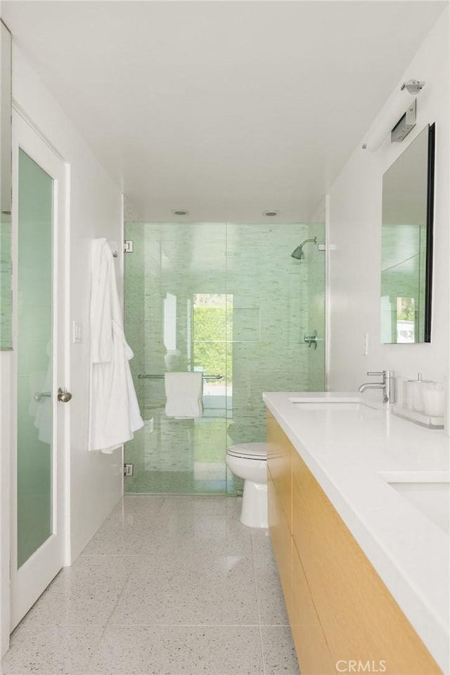 bathroom with double vanity, toilet, a shower stall, and speckled floor
