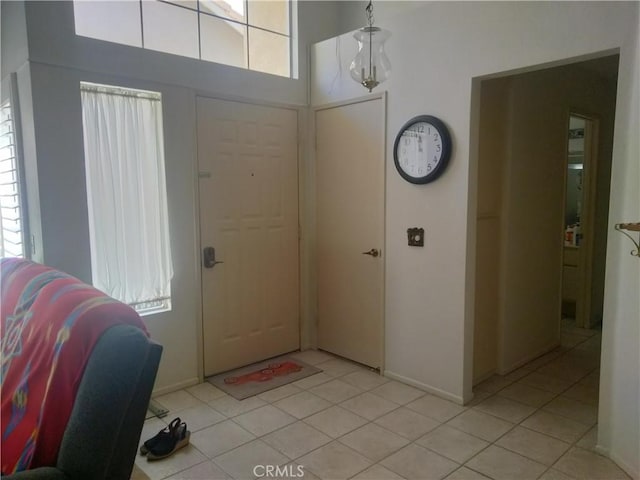 entrance foyer with a towering ceiling, baseboards, and light tile patterned floors