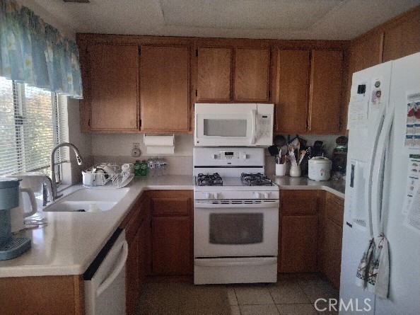 6353 Colonial Ave, Banning, CA 92220 - kitchen featuring white appliances, a sink, brown cabinets, light countertops, and light tile patterned floors