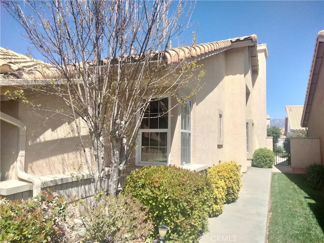 6353 Colonial Ave, Banning, CA 92220 - view of side of property featuring stucco siding, a gate, and a tile roof
