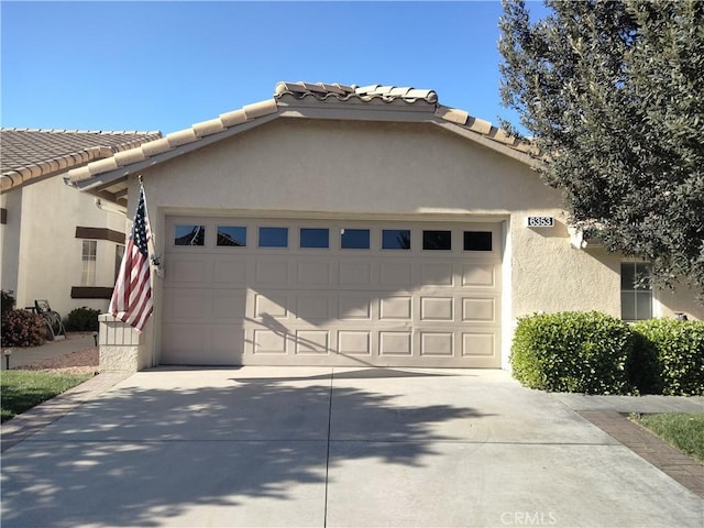 exterior space with stucco siding, driveway, a tiled roof, and a garage