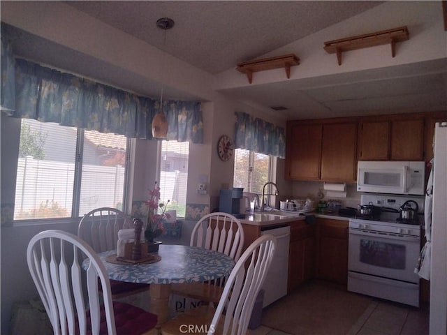 kitchen with a sink, lofted ceiling, white appliances, brown cabinets, and light tile patterned floors
