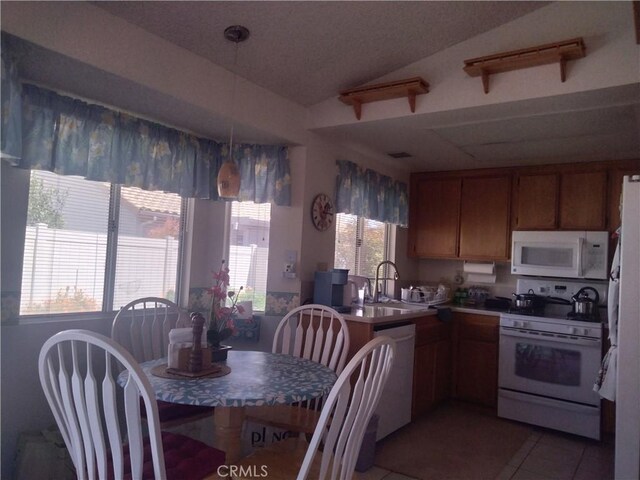 6353 Colonial Ave, Banning, CA 92220 - kitchen featuring white appliances, a sink, light tile patterned floors, brown cabinetry, and lofted ceiling