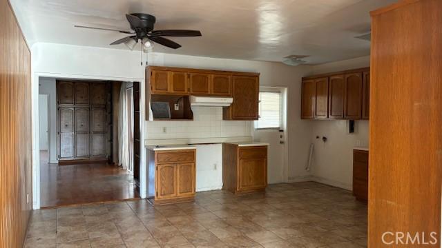 432 Oakford Dr, Los Angeles, CA 90022 - kitchen featuring a ceiling fan, brown cabinetry, under cabinet range hood, and backsplash