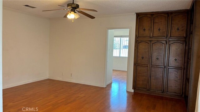432 Oakford Dr, Los Angeles, CA 90022 - unfurnished bedroom featuring wood finished floors, a textured ceiling, ornamental molding, baseboards, and ceiling fan