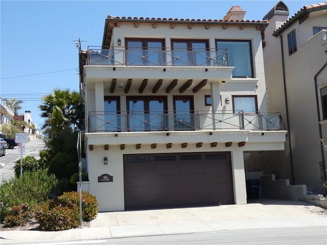 304 27th St, Manhattan Beach, CA 90266 - view of front facade featuring a balcony, stucco siding, an attached garage, driveway, and a tiled roof
