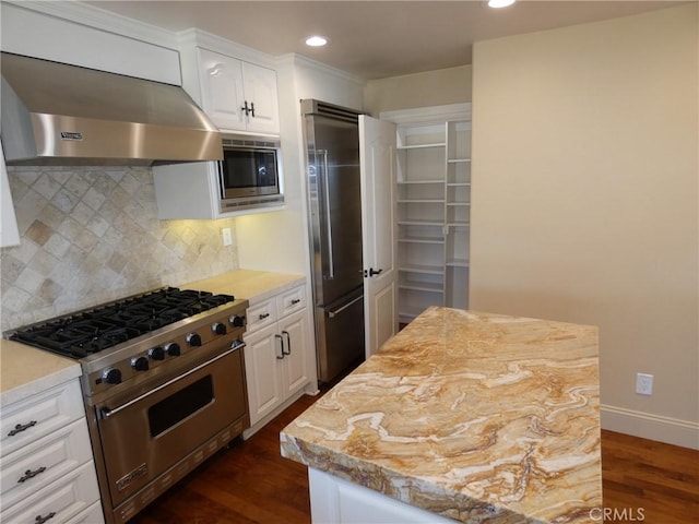 304 27th St, Manhattan Beach, CA 90266 - kitchen featuring high quality appliances, wall chimney range hood, dark wood-style flooring, tasteful backsplash, and white cabinets