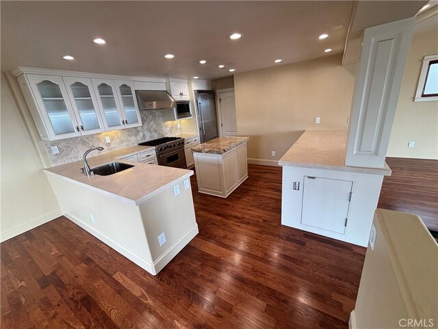 304 27th St, Manhattan Beach, CA 90266 - kitchen featuring wall chimney exhaust hood, a peninsula, stainless steel appliances, backsplash, and dark wood finished floors