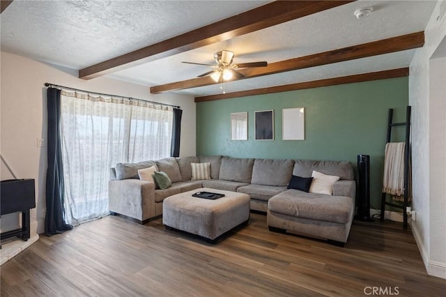 living area with ceiling fan, a textured ceiling, beam ceiling, and wood finished floors