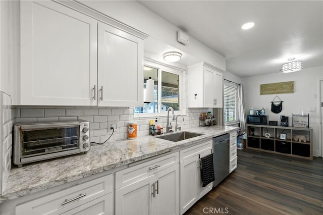 kitchen with a toaster, white cabinets, decorative backsplash, dishwasher, and a sink