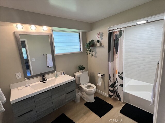 bathroom featuring toilet, wood finished floors, shower / tub combo, and vanity