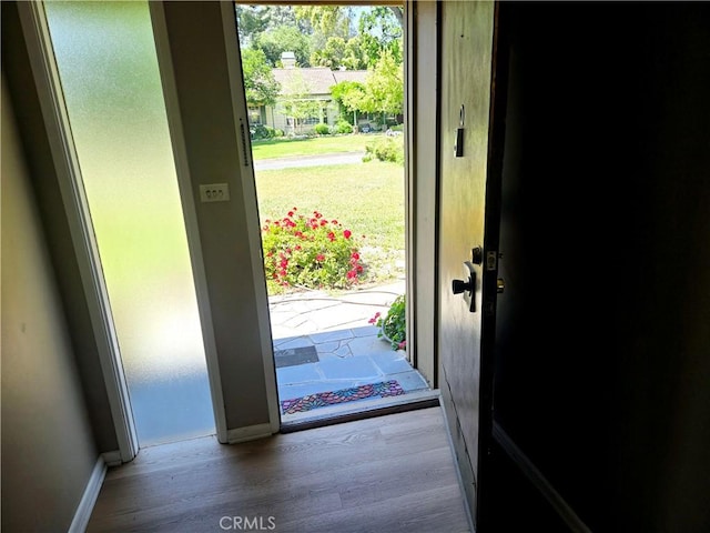 doorway to outside with baseboards and wood finished floors