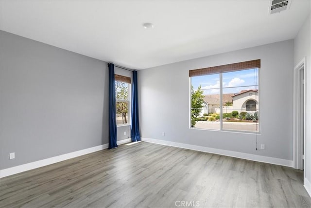 empty room featuring visible vents, baseboards, and wood finished floors
