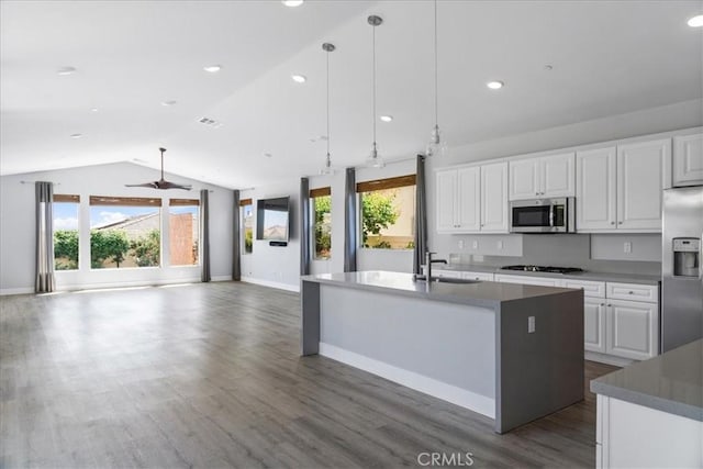 kitchen with dark wood-style flooring, vaulted ceiling, a sink, baseboards, and stainless steel appliances