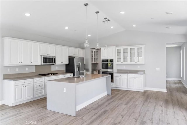 kitchen featuring visible vents, a kitchen island with sink, glass insert cabinets, white cabinetry, and stainless steel appliances