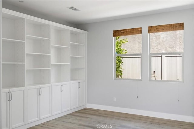 spare room with light wood-style floors, baseboards, and visible vents