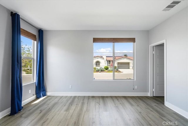 empty room with baseboards, light wood-style flooring, and visible vents
