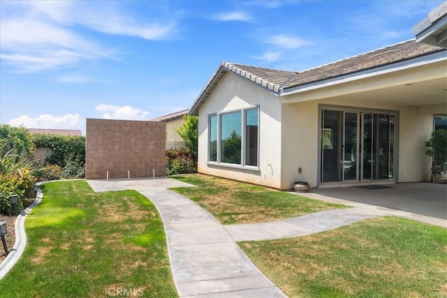 exterior space featuring a patio, stucco siding, and a yard
