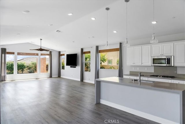 kitchen featuring vaulted ceiling, gas stovetop, a sink, baseboards, and stainless steel microwave