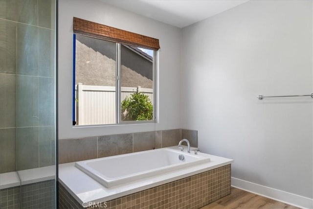 full bathroom featuring baseboards, plenty of natural light, a bath, and wood finished floors