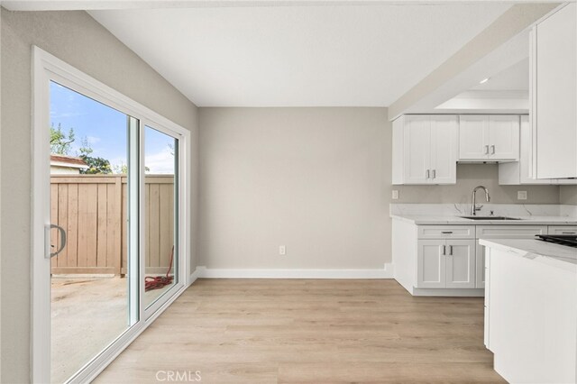 26497 Calle San Francisco Unit 60F, San Juan Capistrano, CA 92675 - kitchen featuring white cabinets, light stone counters, a sink, light wood-style floors, and baseboards
