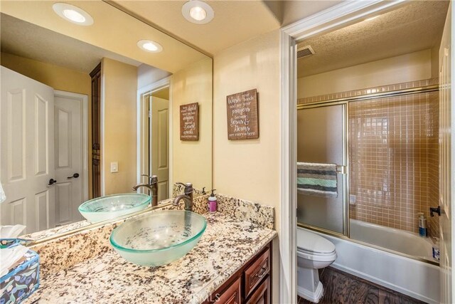 880 E 24th St, Upland, CA 91784 - full bathroom featuring vanity, wood finished floors, toilet, and bath / shower combo with glass door