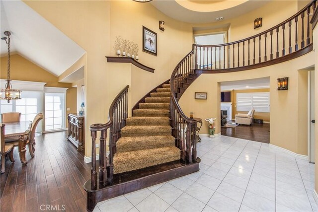 880 E 24th St, Upland, CA 91784 - staircase with high vaulted ceiling, a fireplace, wood finished floors, a chandelier, and baseboards