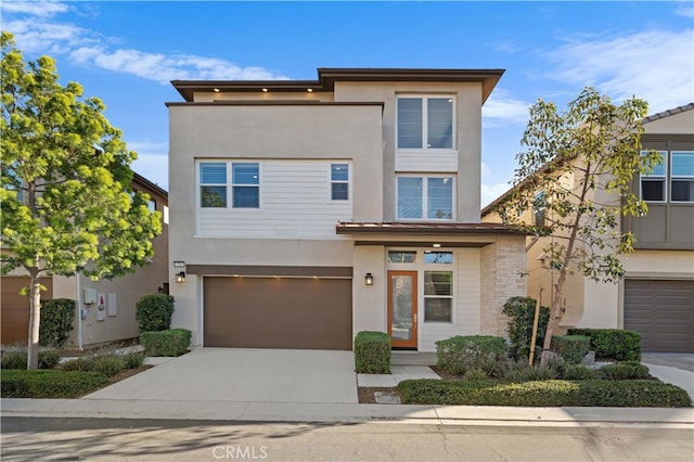 contemporary home featuring stucco siding, a garage, and concrete driveway