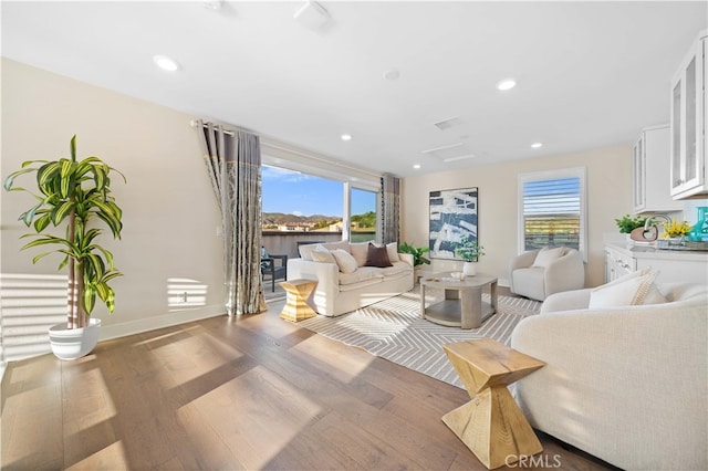 living room with wood finished floors, baseboards, and recessed lighting