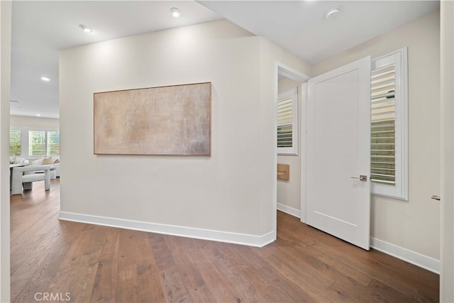 corridor featuring baseboards, recessed lighting, and hardwood / wood-style flooring