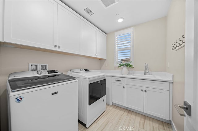 washroom featuring washer and dryer, visible vents, a sink, and cabinet space