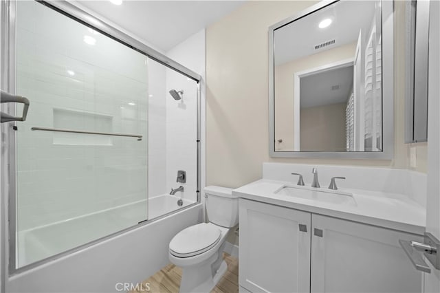 full bathroom with vanity, visible vents, toilet, wood finished floors, and combined bath / shower with glass door