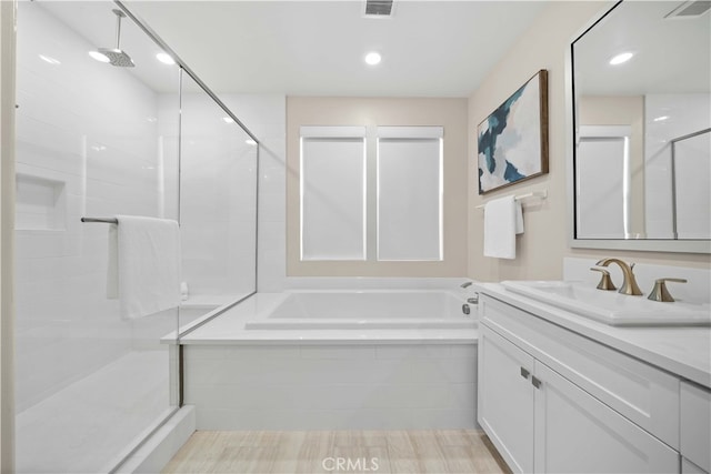 bathroom featuring a stall shower, a garden tub, vanity, and visible vents