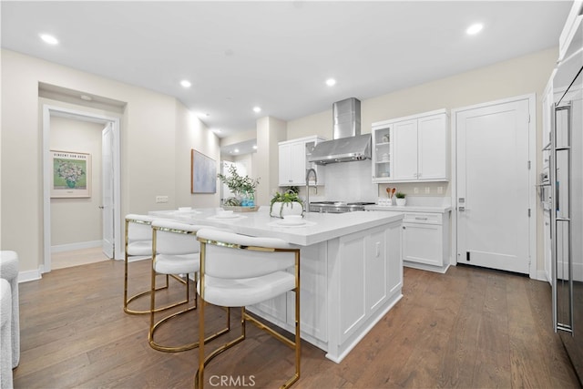 kitchen with light countertops, dark wood-style flooring, wall chimney exhaust hood, and white cabinetry