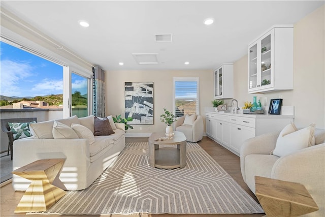 living room featuring light wood-style floors, attic access, visible vents, and recessed lighting