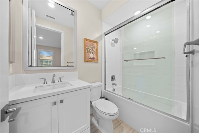 bathroom with visible vents, toilet, enclosed tub / shower combo, vanity, and wood finished floors