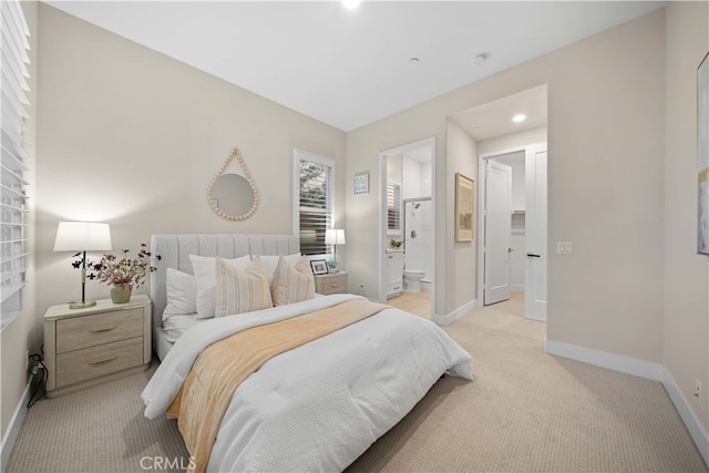 bedroom with baseboards, light colored carpet, and connected bathroom