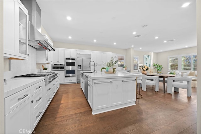 kitchen with light countertops, dark wood finished floors, a kitchen island with sink, and stainless steel appliances