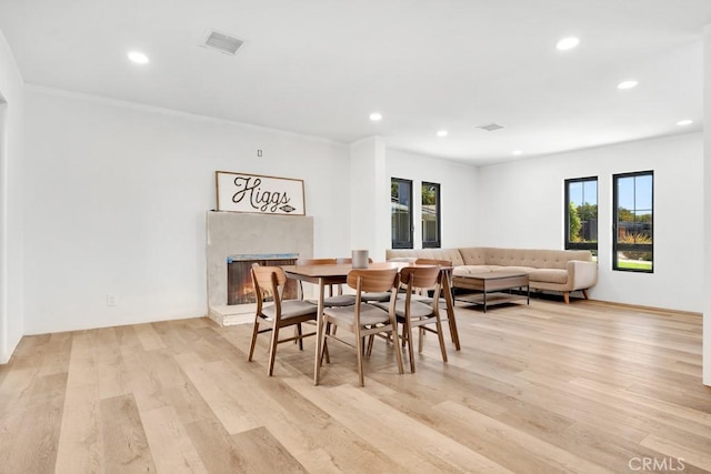 dining room featuring recessed lighting, light wood finished floors, visible vents, and a premium fireplace